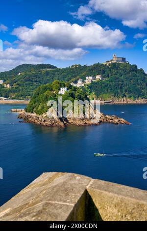 Vista de la Bahia de La Concha desde la Bateria de las Damas, la Isla Santa Clara con la Casa del Faro donde se encuentra la obra Hondalea de la escultora Cristina Iglesias, Al fondo el Monte Igeldo, Donostia, San Sebastian, Ciudad cosmopolita de 187,000 habitantes, destaca por su gastronomía, playas urbanas y edificios inspirados en la arquitectura parisina, Gipuzkoa, Baskenland, Spanien, Europa. Stockfoto