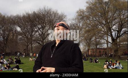 New York, New York, USA, 8. April 2024 an einem schönen Frühlingstag versammeln sich Menschenmassen, um die teilweise Sonnenfinsternis in Sheep's Meadow im New Yorker Central Park zu beobachten Stockfoto