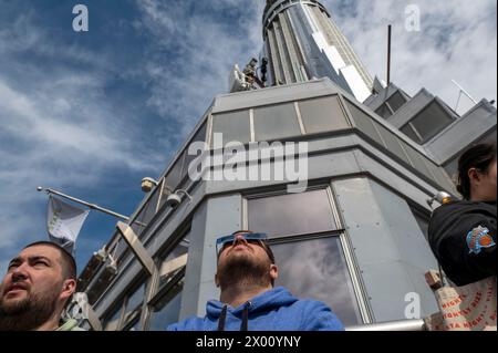 New York, Usa. April 2024. Die Menschen beobachten eine teilweise Sonnenfinsternis von der Aussichtsplattform im 86. Stock des Empire State Building am 8. April 2024 in New York City. Mit der ersten Sonnenfinsternis, die seit sieben Jahren Nordamerika durchquerte, war New York City nicht auf dem Weg der Totalität, da nur 90 % der Sonne vom Mond bedeckt waren; die nächste Sonnenfinsternis, die in den Vereinigten Staaten zu sehen ist, wird 2044 sein. Quelle: SOPA Images Limited/Alamy Live News Stockfoto