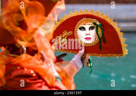 Porträt einer maskierten Frau in einem kreativen Kostüm, das Gesicht spiegelt sich in einem Spiegel, der den venezianischen Karneval feiert. Stockfoto