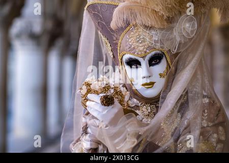 Porträt einer maskierten Frau in einem kreativen Kostüm, posiert vor dem Palazzo Ducale, um den venezianischen Karneval zu feiern. Stockfoto