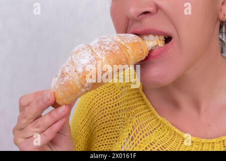 Eine Frau, deren Gesicht nicht sichtbar ist, isst ein Croissant. Stockfoto