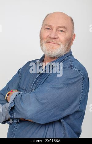 Porträt eines attraktiven und fröhlichen grauhaarigen Mannes in einem Jeanshemd isoliert auf grauem Hintergrund. Stockfoto