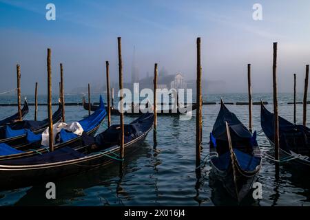 Gondeln, die traditionellen venezianischen Ruderboote, werden am Canale della Giudecca, Insel und Kirche San Giorgio di Maggiore, in Nebel gehüllt, befestigt Stockfoto