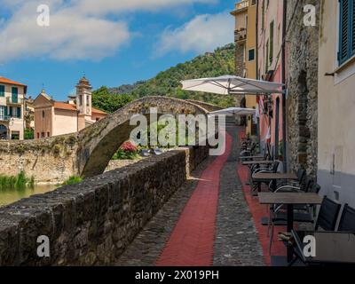 Enge kopfsteingepflasterte Straße als mittelalterliche Steinbrücke und kleine Kirche im Hintergrund in der Altstadt von Dolceacqua, Italien. Stockfoto