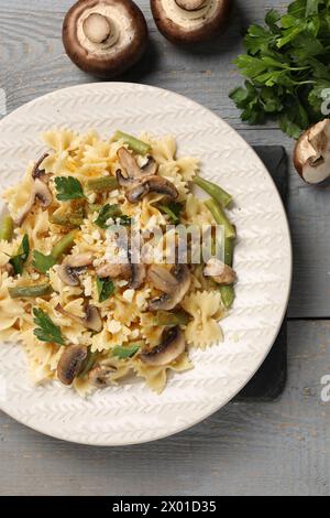 Vegetarische Pasta mit Pilzen, Petersilie, Bohnen und Käse auf grauem Holztisch, Blick von oben Stockfoto