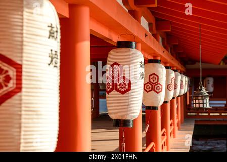 Papierlaternen hängen an den Holzvorsprüngen eines Gehwegs am Itsukushima Shinto-Schrein auf Miyajima, Hiroshima, Japan. Stockfoto