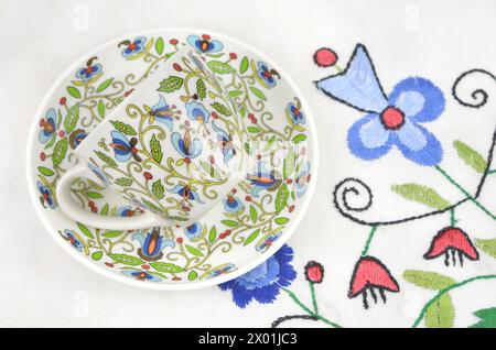 Kaschubische Handwerkskunst: Tasse mit traditioneller Dekoration und gestickter Tischdecke. Stockfoto