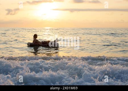 Mann schwimmt auf aufblasbarer Matratze im Meerwasser. Sommer Entspannung und Strandurlaub Stockfoto