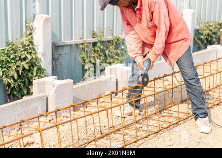 Bauarbeiter, die Stahlbewehrungsstäbe schneiden, bereiten auf der Baustelle Beton-Schalungen vor. Stockfoto