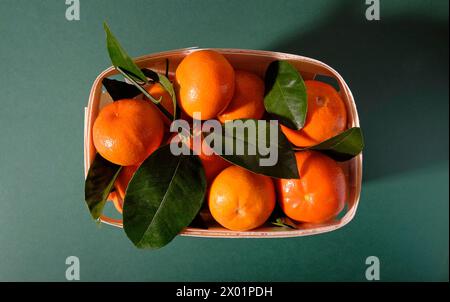 satsuma-Orangen in Holzbehälter auf grünem Hintergrund Stockfoto