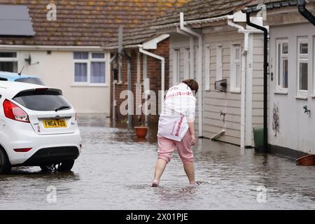 Ein Bewohner wate durch Hochwasser im Rope Walk in Littlehampton, West Sussex, nachdem der Fluss Arun über Nacht seine Ufer geplatzt hat. Der West Sussex Fire and Rescue Service warnte die Menschen in Littlehampton vor schweren Überschwemmungen im Gefolge des Sturms Kathleen. Bilddatum: Dienstag, 9. April 2024. Stockfoto