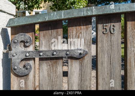 VAXHOLM, SCHWEDEN - 11. AUGUST 2018: Ein Eisenscharnier an einem verwitterten Holztor zu einem skandinavischen Haus zeigt die Nummer 56. Stockfoto