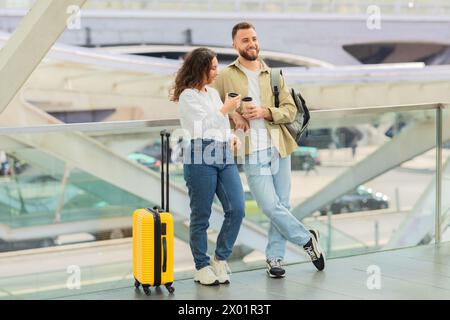 Mann und Frau mit Takeaway-Coffee Warten Flug am Flughafen Stockfoto