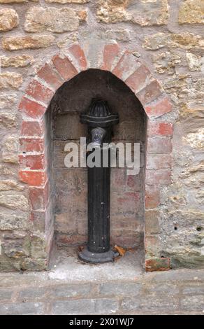 Altes gusseisernes Wasserstandrohr in einer Alkove, die in die Wand eines alten Weberhauses in Sheppards Barton in der historischen Stadt Frome in Somerset gesetzt ist. Stockfoto