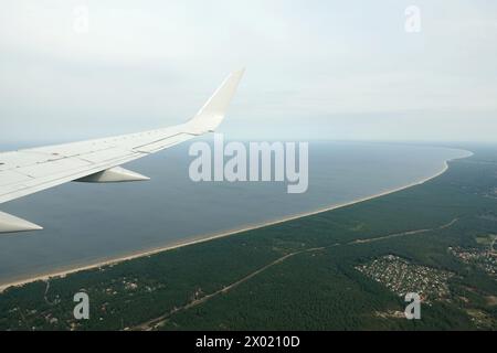 Küste des Golfs von Riga mit langen Sandstränden auf der Ostsee unter fliegendem Flugzeugflügel an bewölktem Tag Stockfoto