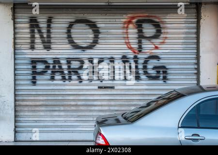 MUHARRAQ, BAHRAIN - 10. FEBRUAR 2018: Ein Auto parkt vor einem handgefertigten Schild ohne Parken, das auf den Fensterläden einer privaten Garage gemalt ist. Stockfoto