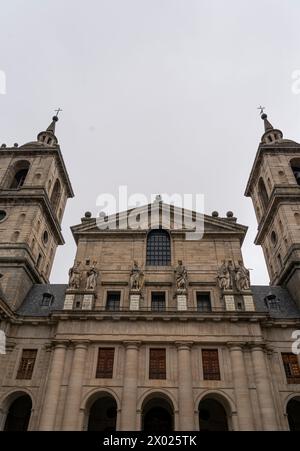 Statuen historischer Persönlichkeiten stehen über dem Innenhof des Klosters El Escorial, gegen die strenge Eleganz der Fassade des Gebäudes. Stockfoto