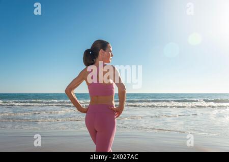 Sportliche Frau mit Blick auf das Meer vor dem Schwimmen oder Surfen im Meer Stockfoto