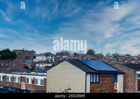 Vorstadtlandschaft mit Wohnhäusern mit Solarpaneelen unter einem dynamischen blauen Himmel mit schimmernden Wolken, die nachhaltiges Wohnen in einem modernen Stil zeigen Stockfoto