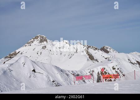 Schneebedeckter Berggipfel mit Skipisten und Lawinenwarnschildern. Stockfoto