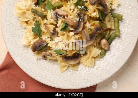 Vegetarische Pasta mit Pilzen, Petersilie, Bohnen und Käse auf orangefarbenem Tisch, Blick von oben Stockfoto