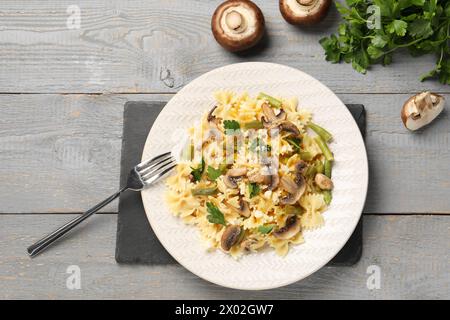 Vegetarische Pasta mit Pilzen, Petersilie, Bohnen und Käse auf grauem Holztisch, Blick von oben Stockfoto