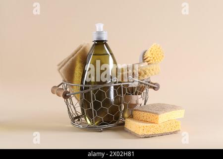 Flasche Reinigungsmittel, Schwämme und Bürsten auf beigem Hintergrund Stockfoto