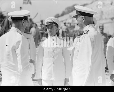 DER KÖNIG AUF DER GEORGE CROSS ISLAND. 20. JUNI 1943, MALTA. WÄHREND SEINES BESUCHS AUF MALTA UNTERNAHM DER KÖNIG EINE AUSGEDEHNTE TOUR DURCH DIE BOMBARDIERTE WERFT. ER SPAZIERTE ENTLANG DER RUINEN DER VIEL BOMBARDIERTEN SENGLEA UND INSPIZIERTE DAS GEORGE CROSS, DAS ER DER INSEL VERLIEHEN HATTE. ALS DER KÖNIG UND LORD GORT DIE STRASSEN FUHREN, WAR IHR AUTO MIT BLUMEN GEFÜLLT, DIE VON DEN MENSCHENMASSEN GEWORFEN WURDEN. - Der König geht an Land bei Custom House, Malta. Auf ihn wartet Viscount Gort, VC, Generalgouverneur von Malta. Hinter ihm steht Captain A W Clarke, Stabschef des Gouverneurs Stockfoto