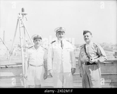 MIT DEM VILLE D'ORAN. 31. MAI 1945, HAFEN VON ALEXANDRIA. KRIEGSGEFANGENE WURDEN AUF DEM FRANZÖSISCHEN SCHIFF AUS DEUTSCHEN GEFANGENENLAGERN IN NORDITALIEN ZURÜCKGEBRACHT. - Der Captain der VILLE D'ORAN mit seinen Verbindungs- und Troopingoffizieren. Von links nach rechts: Jnr Lieut Jacques Quilici aus Marseille, Verbindungsoffizier; Captain de Corvette Louis Eyglier aus Marseille, Kapitän der VILLE D'ORAN; und Lieut John Moriarty aus London, OC-Truppen an Bord der VILLE D'ORAN Stockfoto