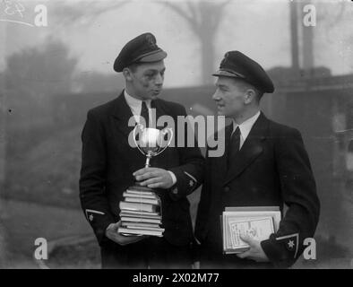 DER FÜNFTE SEE LORD INSPIZIERT MARINEFLUGLEHRLINGE UND ÜBERREICHT PREISE. 12. UND 13. DEZEMBER 1944 HMS DAEDALUS II., ROYAL MARINEFLUGSTATION, NEWCASTLE-UNDER-LYME. VIZEADMIRAL D W BOYD, CB, CBE, DSC, FIFTH SEA LORD, INSPEKTION VON MARINEFLUGAUSZUBILDENDEN. - Links: Chief Petty Officer Naval Air Apprentice K T Martin, aus Plymouth mit Preisen und dem Pokal, den er als Kapitän des Rugby-Teams gewann, und (rechts) Chief Petty Officer Naval Air Apprentice R L Routledge, aus Carlisle mit Preisen, die bei der Durchgangsprüfung gewonnen wurden Stockfoto