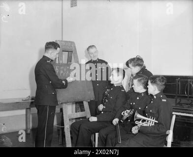 DER 14-JÄHRIGE JUNGE IST MITGLIED DER ROYAL MARINES BAND. 8. JANUAR 1942, SCARBOROUGH. DER 14-JÄHRIGE REGINALD DAVID WARDEN TRAT DER ROYAL MARINE SCHOOL OF MUSIC IN SCARBOROUGH BEI UND WURDE IHR JÜNGSTES MITGLIED. DIE SCHULE VERSORGT ALLE MUSIKER UND MARINEBANDS MIT HM-SCHIFFEN UND LANDBASEN. - Im Musikunterricht, um seinen Musikunterricht zu bekommen. Er steht hinter den anderen drei Jungen Stockfoto