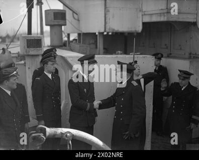 IM KAMPF GEGEN DIE FRANZÖSISCHE CORVETTE VERSENKT 2 U-BOOTE. AM 14. MÄRZ 1943 VERSENKTE GREENOCK, DIE FRANZÖSISCHE CORVETTE ACONIT, ZWEI U-BOOTE VON GUNFIRE UND RAMMTE, WÄHREND SIE AM 10. MÄRZ 1943 EINEN ATLANTIKKONVOI DURCH EIN U-BOOT-PACK BEGLEITETE. DAS ZWEITE U-BOOT HATTE GERADE DEN BRITISCHEN ZERSTÖRER HMS HARVESTER TORPEDIERT. DIE ACONIT FUHR ZU EINEM BRITISCHEN HAFEN MIT ÜBERLEBENDEN DES ERNTEERS UND EINEM KAUFMANN UND GEFANGENEN AUS DEN BEIDEN U-BOOTEN. - Vizeadmiral Truppe, Flaggenoffizier in Glasgow, gratulierte Leutnant de Vaissea Jean Levasseur, 32 Jahre alter kämpfender Franzose, Kapitän der FFS ACONIT an Bord der Co Stockfoto