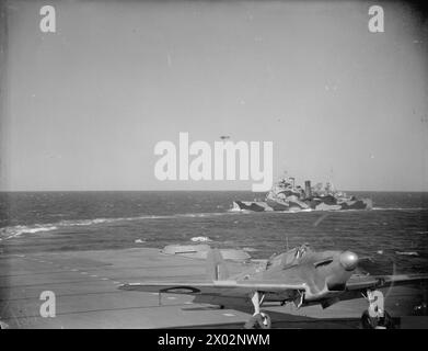 BRITISCHE UND US-AMERIKANISCHE FLUGZEUGE UND KRIEGSSCHIFFE DECKEN DEN RUSSISCHEN KONVOI AB. MAI 1942, AN BORD DER HMS SIEGREICH AUF SEE UND IN HVALFJORD, ISLAND. - Ein Fairey Fulmar auf dem Flugdeck der HMS SIEGREICH mit dem Kreuzer HMS LONDON im Hintergrund Royal Navy, LONDON (HMS), Schlachtschiff Stockfoto