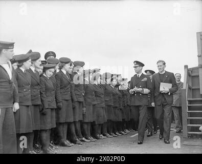 DER KÖNIG BESUCHT DIE HEIMATFLOTTE. 15. AUGUST 1943, SCAPA FLOW. DER KÖNIG BESUCHTE MÄNNER UND SCHIFFE DER HEIMATFLOTTE, ER GING AN BORD DES FLOTTENFÜHRERS HMS ONSLOW, DER IHN ZUM FLAGGSCHIFF HMS DUKE OF YORK BRACHTE. HIER TRAF DER KÖNIG AUF ADMIRAL SIR BRUCE A FRASER, KBE, CB, C-IN-C-FLOTTE. - Der König verlässt die Hütte der Church of Scotland, beobachtet von Mitgliedern der WRNS Stockfoto