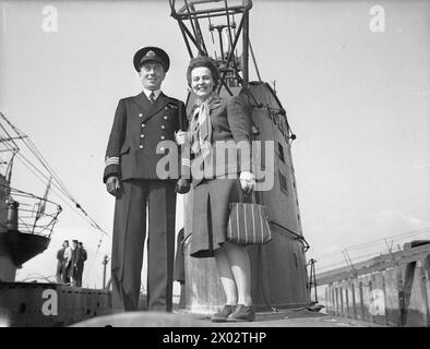 DIE POLNISCHE MARINE IN GROSSBRITANNIEN, 1939-1947: Lieutenant Jerzy 'George' Koziołkowski, CO von ORP Sokół, mit seiner polnischen Frau, die Korporal der britischen WAAF an Bord des U-Bootes ist. Zwei polnische U-Boote, ORP Dzik (Wildschwein) und die berühmte ORP Sokół (Falke), sind nach erfolgreichen Patrouillen im Mittelmeer am 31. März 1944 nach Plymouth zurückgekehrt. ORP Dzik hat gerade ihren ersten einsatz beendet. Ein Jahr lang arbeitete sie im Mittelmeer, und ihre Jolly Roger Erfolgsfahne zeugt von der Anzahl ihrer Siege dort.ORP Sokół wurde von Kapitän Eugeniusz Pławski, der polnischen Marine Chi, begrüßt Stockfoto