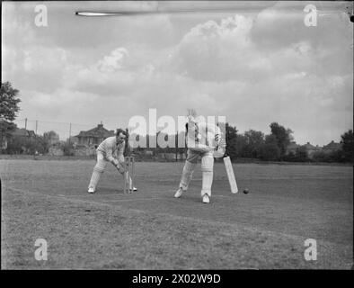 CRICKET-SPIEL: BERICHTERSTATTUNG ÜBER EIN SPIEL ZWISCHEN KENTON UND ALEXANDRA PARK, KENTON, MIDDLESEX, ENGLAND, GROSSBRITANNIEN, 1945: der Schlagmann trifft den Ball, während der Wicket Keeper bei einem Cricket-Spiel zwischen Kenton und Alexandra Park auf dem Kenton Ground zugreift Stockfoto