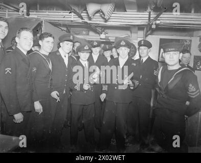 WEIHNACHTSSZENEN AN BORD DER HMS VICTORIOUS. AM 25. DEZEMBER 1941 AN BORD DES FLUGZEUGTRÄGERS BEI SCAPA FLOW. - Große Besuchsrunden. Ein Vorweihnachtsprolog, der in der Navy gewährt wird, wenn sich das jüngste Mitglied der Schiffskompanie in der Uniform des Kapitäns verkleidet und eine Inspektion des Schiffes durchführt. Hier ein Junge, T Caygill, verkleidet als Captain, und ein anderer Junge, T Hoy, verkleidet als Commander, inspizieren das Chaos der PO während ihrer „Besuchsrunden“ Stockfoto