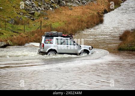 Land Rover überquert einen Fluss im Elan Valley, Powys, Wales, Großbritannien. Stockfoto