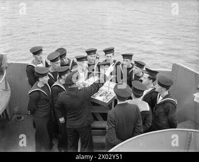 ENTWÄSSERUNG DES ROYAL NAVY-ZUGES AUF DEM MODERNEN SCHULSCHIFF. SEPTEMBER 1941 AN BORD DES ZERSTÖRER-DEPOT-SCHIFFES HMS TYNE. DIE DESTROYERMEN SIND AUSGEBILDET IN GESCHÜTZE, TORPEDOFEUER, U-BOOT-ABWEHR, SEEMANNSCHAFT UND SIGNALGEBUNG. ES WERDEN SCHIFFSMODELLE VERWENDET UND DIE BELEUCHTUNG IST SO ANGEORDNET, DASS SIE DIE EFFEKTE VON SCHEINWERFERN, STERNMUSCHELN UND GESCHÜTZBLITZEN ERZEUGT. - KEIN ABDRUCK Stockfoto