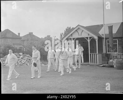 CRICKET-SPIEL: BERICHTERSTATTUNG ÜBER EIN SPIEL ZWISCHEN KENTON UND ALEXANDRA PARK, KENTON, MIDDLESEX, ENGLAND, GROSSBRITANNIEN, 1945 verlässt Ein Cricket-Team den Pavillon und beginnt, während eines Spiels zwischen Kenton und Alexandra Park auf dem Kenton Ground zu spielen Stockfoto