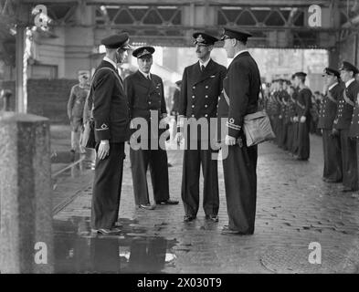 KÖNIG HAAKON VON NORWEGEN BESUCHT PLYMOUTH UND DAS NORWEGISCHE MARINEDEPOT UND AUSBILDUNGSEINRICHTUNG. 11. OKTOBER 1941. KRONPRINZ OLAV BEGLEITETE KÖNIG HAAKON AUF DEM BESUCH. - König Haakon mit Kronprinz Olav unterhält sich mit norwegischen Marineoffizieren in Mill Bay Stockfoto