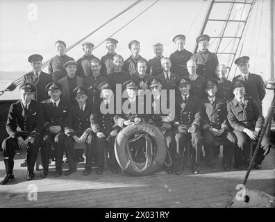 KREUZKANALDAMPFER JETZT ERHOLUNGSSCHIFF FÜR SEELEUTE. JUNI 1943, SCAPA FLOW. DER KREUZKANALDAMPFER AUTOCARRIER, DER FRÜHER URLAUBSWAGEN VON UND NACH FRANKREICH TRANSPORTIERTE, IST HEUTE EIN ERHOLUNGSSCHIFF FÜR DIE BESATZUNGEN DER VIELEN HILFSKRAFTSCHIFFE DER HEIMATFLOTTE, DIE SICH UM DEN SERVICE DER ROYAL NAVY KÜMMERN. ES IST DAS ERSTE UND EINZIGE SEINER ART, UND FÜR TAUSENDE VON MÄNNERN BEDEUTET ES EINMAL PRO WOCHE BIER UND "FLICKS". - Eine Gruppe von Offizieren und Männern des AUTOCARIER, die bei der Unterhaltung an Bord helfen Stockfoto