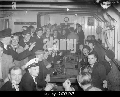 KREUZKANALDAMPFER JETZT ERHOLUNGSSCHIFF FÜR SEELEUTE. JUNI 1943, SCAPA FLOW. DER KREUZKANALDAMPFER AUTOCARRIER, DER FRÜHER URLAUBSWAGEN VON UND NACH FRANKREICH TRANSPORTIERTE, IST HEUTE EIN ERHOLUNGSSCHIFF FÜR DIE BESATZUNGEN DER VIELEN HILFSKRAFTSCHIFFE DER HEIMATFLOTTE, DIE SICH UM DEN SERVICE DER ROYAL NAVY KÜMMERN. ES IST DAS ERSTE UND EINZIGE SEINER ART, UND FÜR TAUSENDE VON MÄNNERN BEDEUTET ES EINMAL PRO WOCHE BIER UND "FLICKS". - Blick auf die Bar Stockfoto