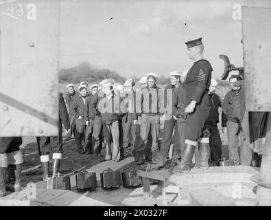 DEMS-SCHÜTZEN HALTEN PACE MIT DEN NEUESTEN KRIEGSWAFFEN. 11. UND 12. NOVEMBER 1943, DEMS RANGES, CARDIFF. DAS DEMS-TRAININGSZENTRUM, IN DEM DIE MÄNNER, DIE FEINDLICHE SEE- UND LUFTANGRIFFE AUF ALLIIERTE HANDELSSCHIFFE ABWEHREN, AUFFRISCHUNGSKURSE ABSOLVIEREN, UM PACE MIT IHREN NEUEN VERTEIDIGUNGSWAFFEN ZU VERSORGEN. - Oerlikon-Geschützvortrag für amerikanische Marineoffiziere, bevor sie auf die Strecke feuern Stockfoto