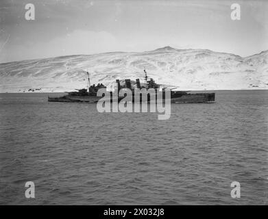 AN BORD DER HMS SIEGREICH. 23. BIS 28. JANUAR 1942 AN BORD DES FLUGZEUGTRÄGERS IN HVALFJORD, ISLAND. HMS VICTORIOUS UND ANDERE SCHIFFE DER FLOTTE PATROUILLIEREN IM NORDATLANTIK AUF DER SUCHE NACH DEM DEUTSCHEN SCHLACHTSCHIFF TIRPITZ. - Der Kreuzer HMS CUMBERLAND kommt in Hvalfjord vor der Patrouille Royal Navy, HMS Cumberland, Fregatte, (1986) Stockfoto