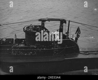 ANKUNFT DES U-BOOTES TRIDENT, DAS DEN DEUTSCHEN KREUZER PRINZ EUGEN TORPEDIERT HAT. 19. MÄRZ 1942 AN BORD DES DEPOT-SCHIFFES HMS FORTH, HOLY LOCH. - Commander G M Sladen, DSO, DSC, RN, Captain der HMS TRIDENT, auf der Brücke mit einigen seiner Offiziere und Mitglieder der Crew, als die HMS TRIDENT neben HMS FORTH kommt Stockfoto