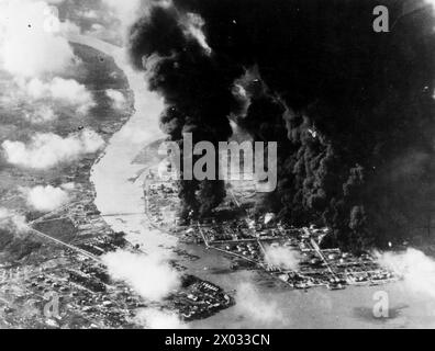 JAPANISCHE ÖLRAFFINERIEN BRENNEN WÄHREND EINES ANGRIFFS BRITISCHER FLUGZEUGE. JANUAR 1945, VON EINEM DER ANGREIFENDEN FLUGZEUGE DER HMS SIEGREICH WÄHREND DES ANGRIFFS AUF DIE JAPANISCHEN ÖLVORRÄTE IN PALEMBANG IM SÜDEN VON SUMATRA DURCH TRÄGERFLUGZEUGE DER OSTINDISCHEN FLOTTE. - Japanisches Öl steigt in dicken Rauchwolken auf, während ein Trägerflugzeug auf Palembang Raffinerien angreift Stockfoto