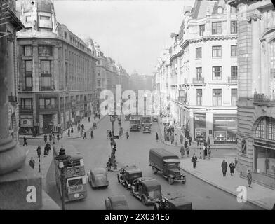 LONDON IS STILL LONDON: DAILY LIFE IN WARTIME LONDON, ENGLAND, FEBRUAR 1941 - Ein weites Bild der Regent Street (vom Piccadilly Circus Ende der Regent Street, während die Straße in Richtung Piccadilly führt), mit Bussen, Autos und Fußgängern, die ihrem täglichen Geschäft nachgehen. Ein großes Geschäft, R W Forsyth, ist links auf dem Foto an der Kreuzung zu sehen, wo die Vigo Street (links) und die Glasshouse Street (rechts) in die Regent Street münden. Interessant ist, dass die Straßenlaternen leer sind, als Teil der Verdunkelung, und in der Mitte der Straße gibt es ein Schild Stockfoto