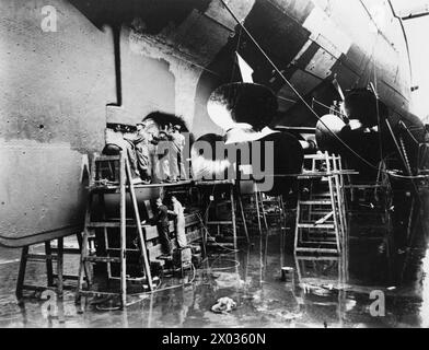 SZENEN AN BORD DER HMS REPULSE WÄHREND IHRES REFIT. 1940 IM TROCKENDOCK. - Arbeiter am Ruder und an den Propellern Stockfoto